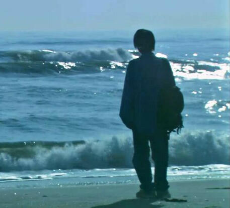 person staring out at blue ocean